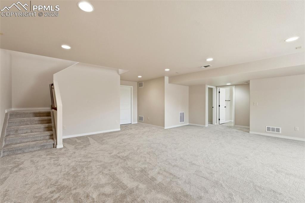 Finished basement with light colored carpet and recessed lighting