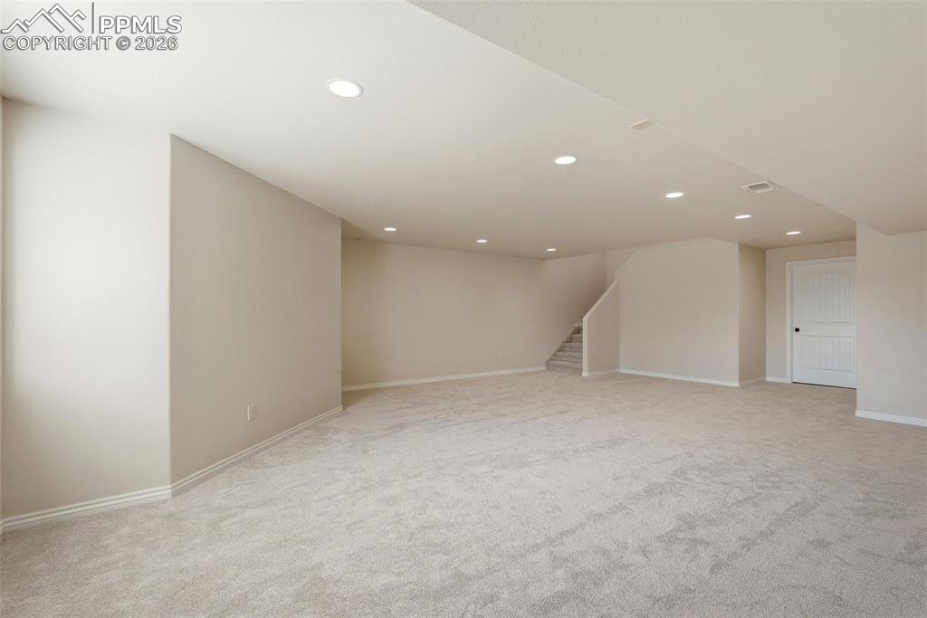 Finished below grade area with light colored carpet and recessed lighting