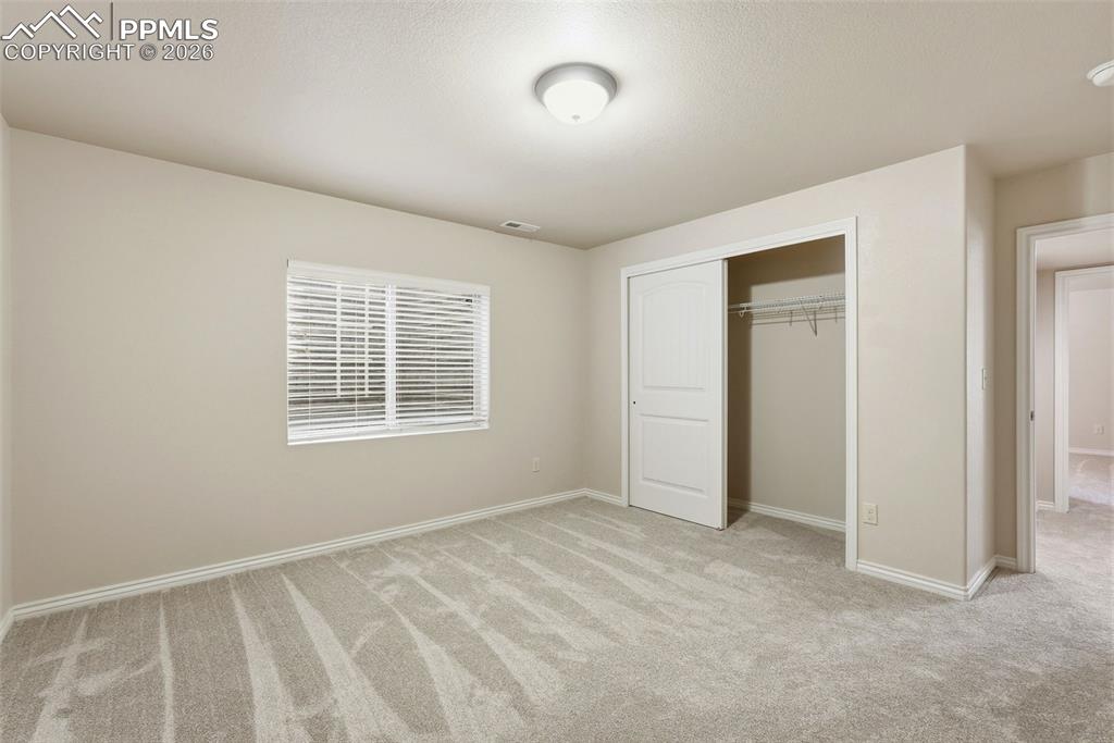 Unfurnished bedroom with light colored carpet and a closet
