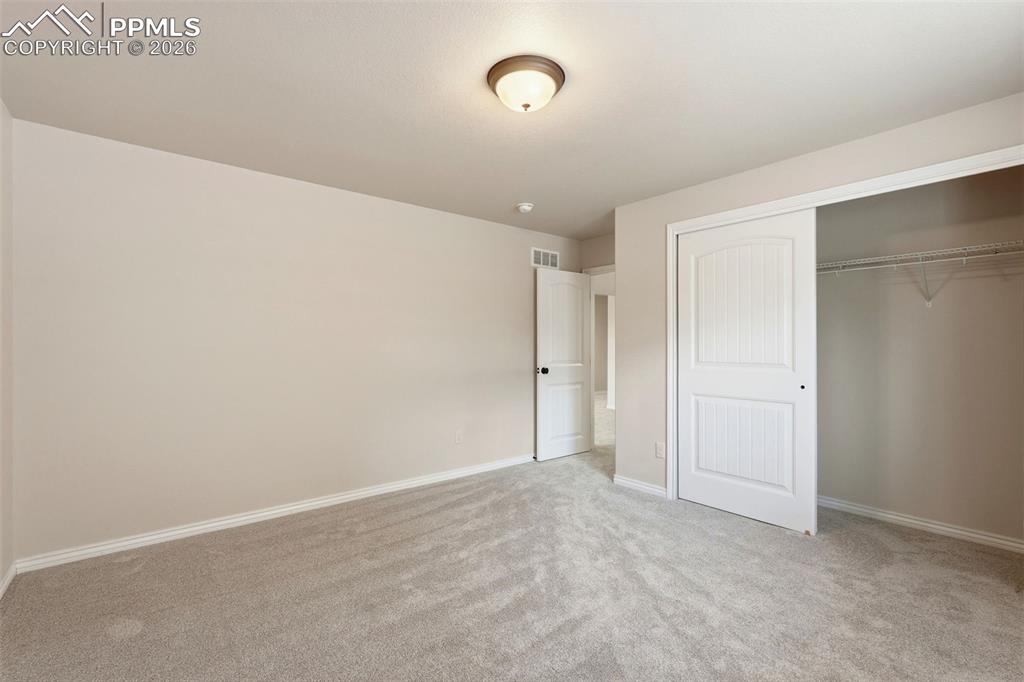 Unfurnished bedroom with light carpet and a closet