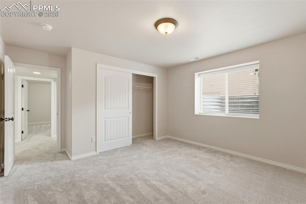 Unfurnished bedroom with light colored carpet and a closet