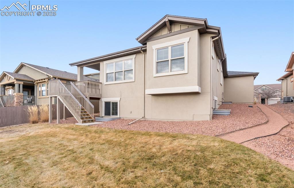 Rear view of house featuring stairs, stucco siding, and a wooden deck