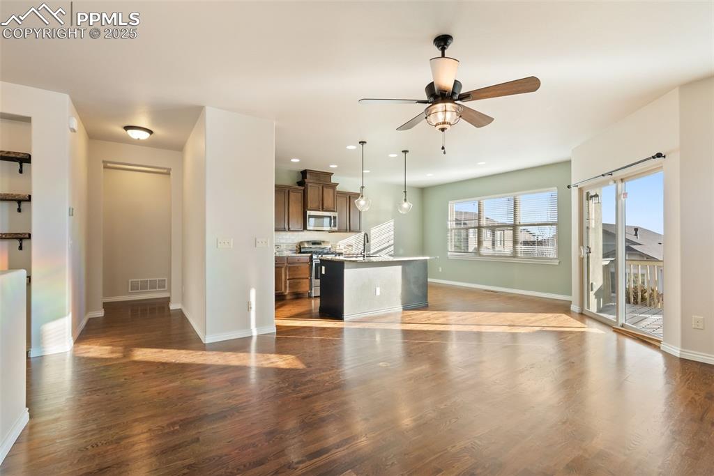 Unfurnished living room featuring dark wood-type flooring, ceiling fan, and recessed lighting
