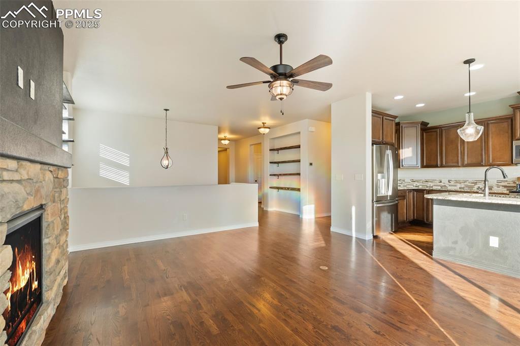 Unfurnished living room featuring a fireplace, dark wood-style floors, and ceiling fan