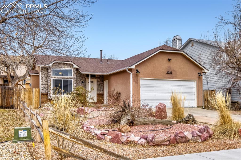 Ranch-style home with stone siding, concrete driveway, a garage, stucco siding, and roof with shingles