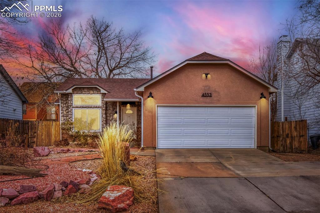 Ranch-style home featuring stone siding, concrete driveway, a garage, and stucco siding