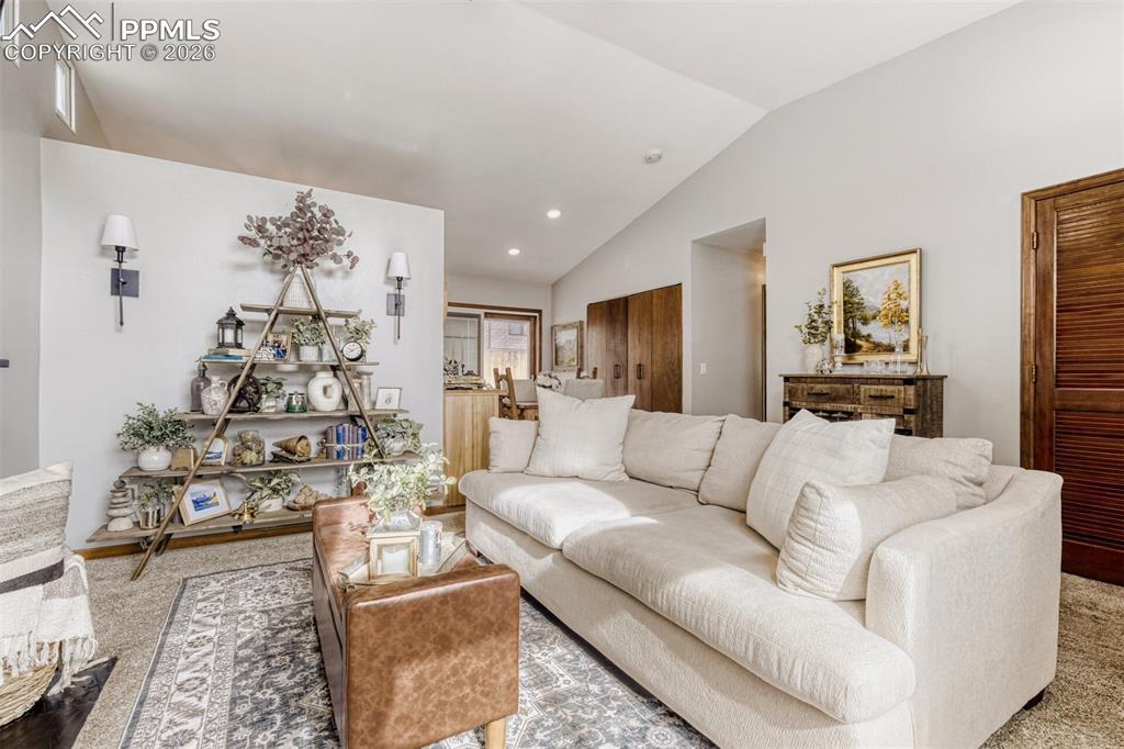Carpeted living room featuring lofted ceiling