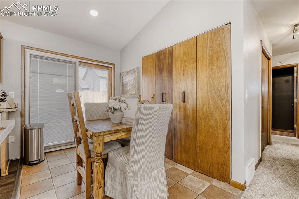 Dining space with vaulted ceiling, light tile patterned floors, recessed lighting, and light carpet