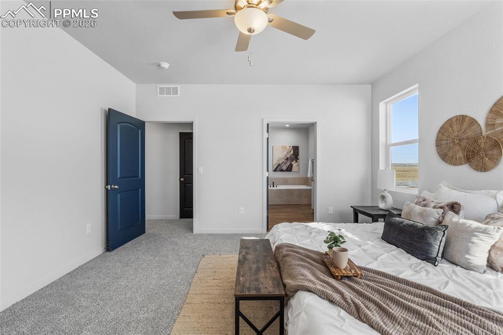 Bedroom featuring light carpet, connected bathroom, and a ceiling fan