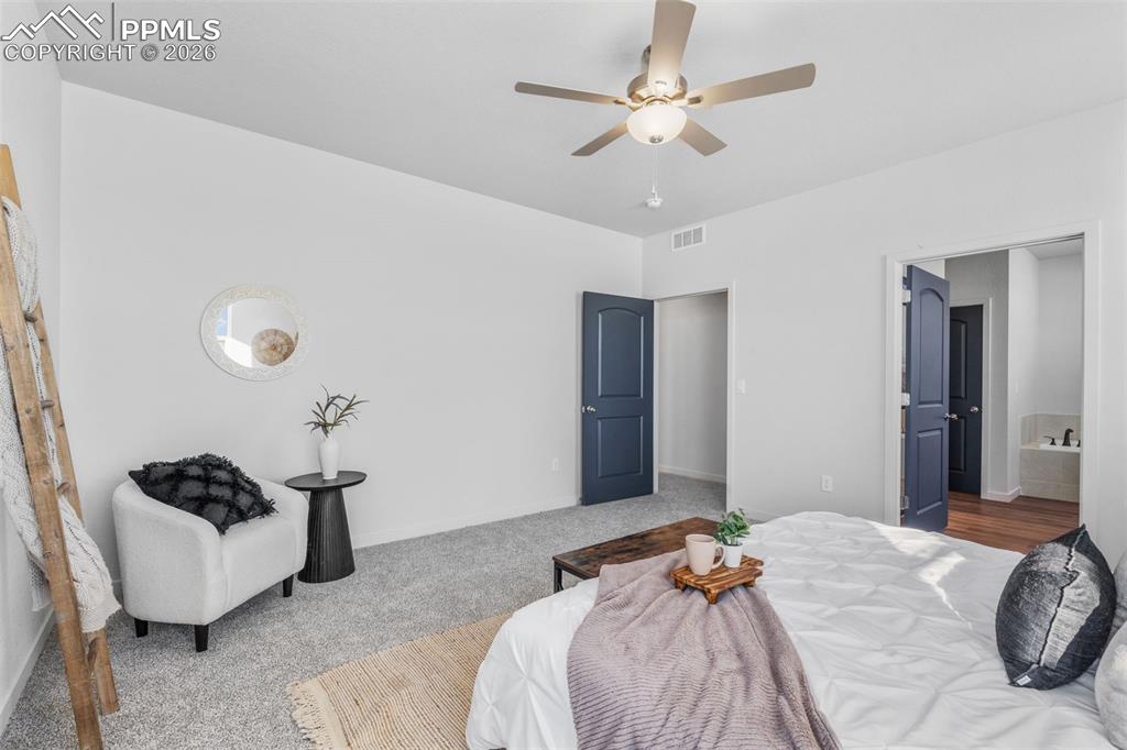 Bedroom with ensuite bath, ceiling fan, and carpet floors