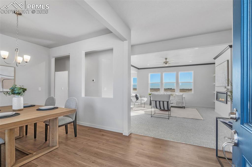 Dining space with light wood-style floors, a fireplace, and a chandelier