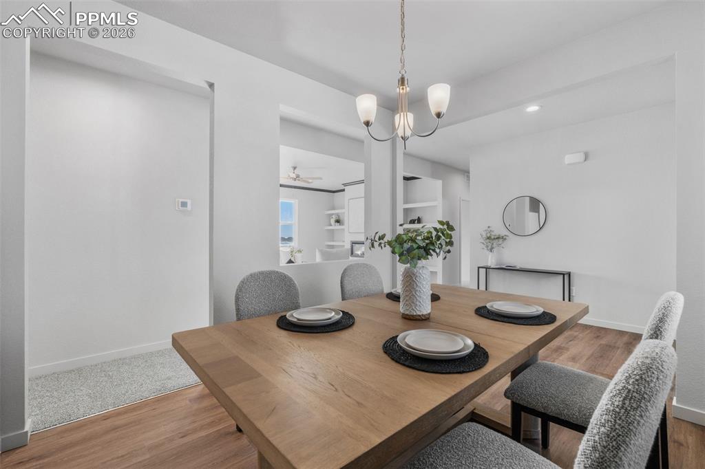 Dining area with light wood-style flooring, a chandelier, and a ceiling fan