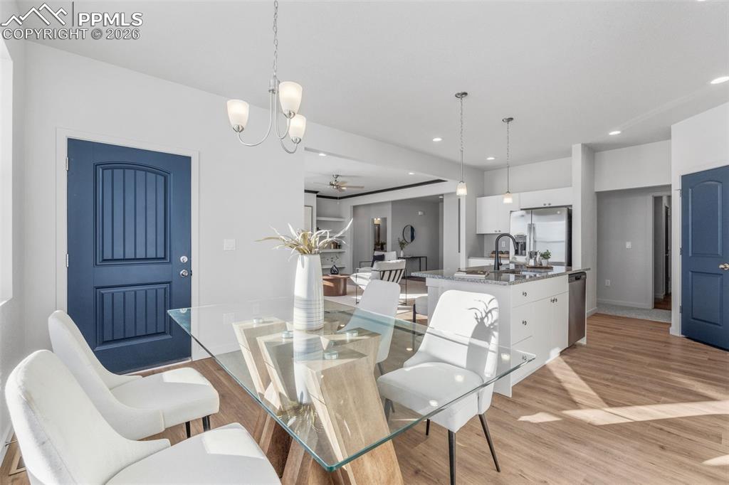 Dining area featuring a ceiling fan, light wood-type flooring, a chandelier, and recessed lighting