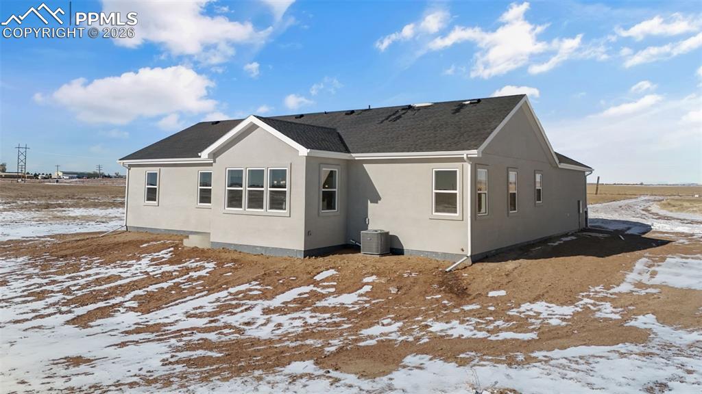 Snow covered property featuring stucco siding and a shingled roof