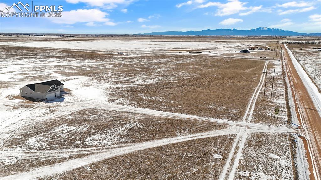 Snowy aerial view with a mountain view and a view of rural / pastoral area