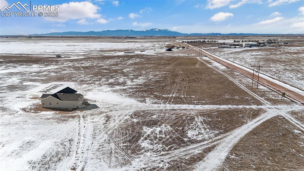 Snowy aerial view featuring a mountain view and a rural view
