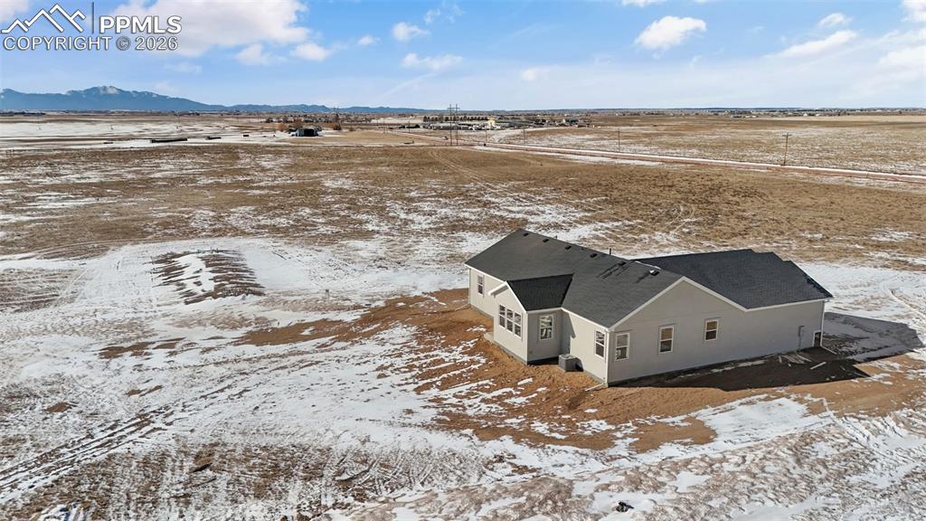 Snowy aerial view featuring a mountain view and a view of countryside
