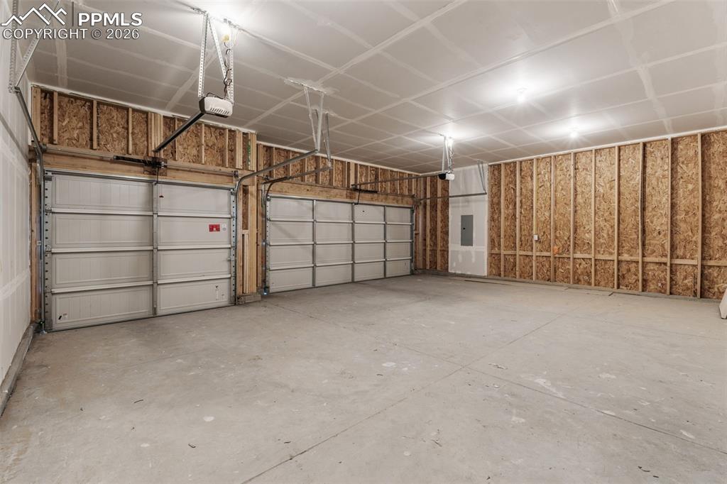 Garage featuring electric panel and a garage door opener