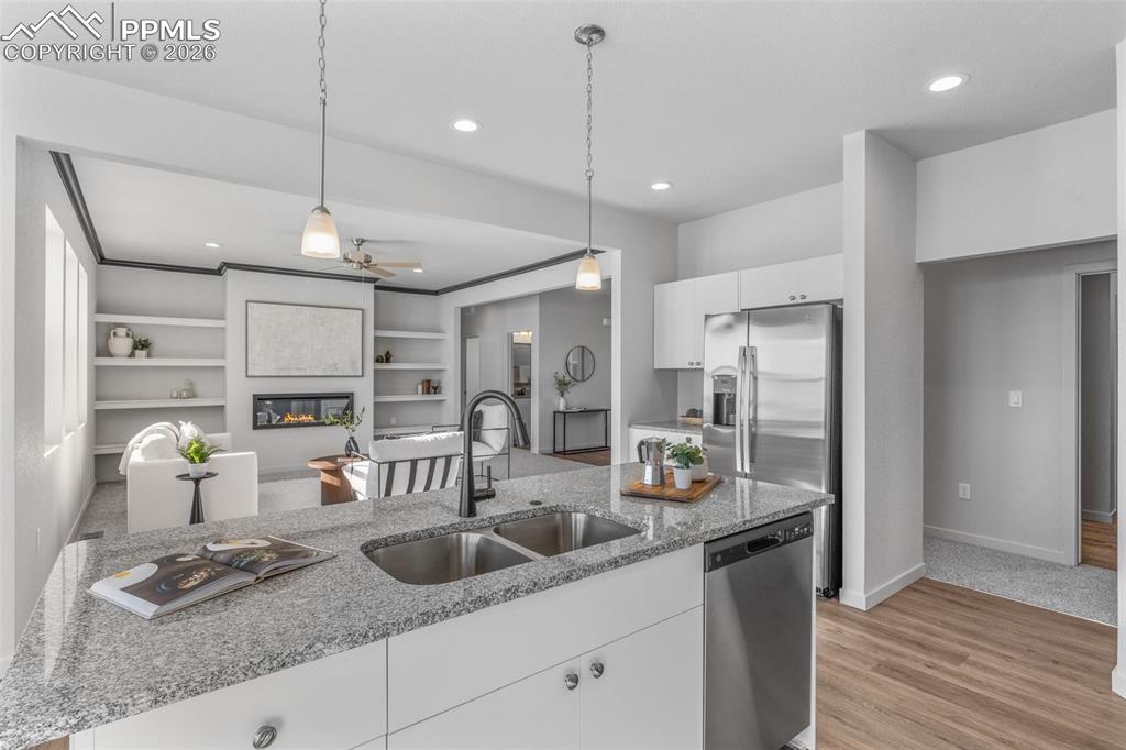 Kitchen with white cabinetry, hanging light fixtures, light stone counters, appliances with stainless steel finishes, and recessed lighting