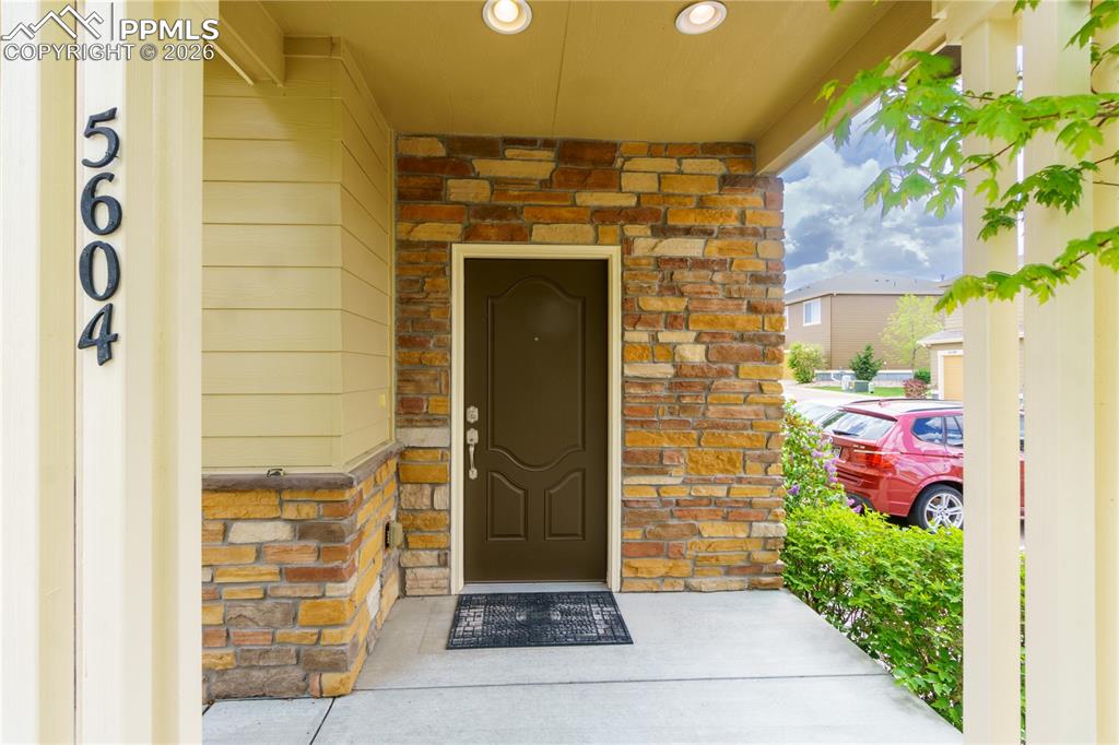 Doorway to property with stone siding and covered porch
