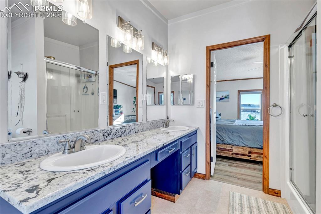 Full bath with a shower stall, ensuite bathroom, double vanity, and crown molding