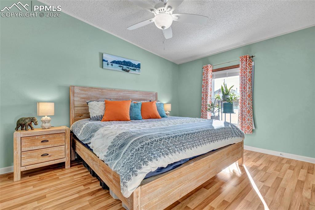 Bedroom featuring light wood finished floors, ceiling fan, and a textured ceiling