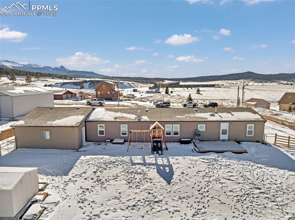 Snow covered property featuring a mountain view and a patio area