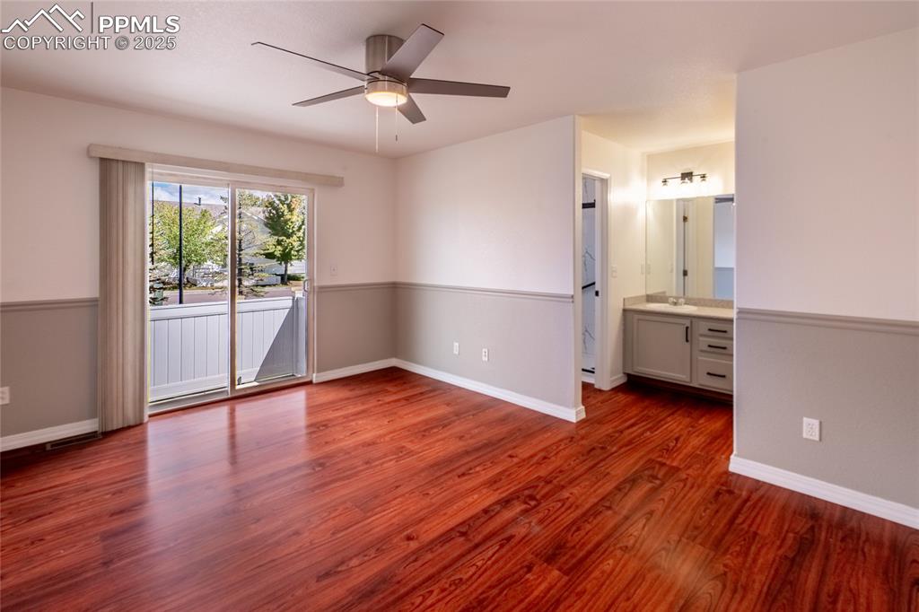 Unfurnished bedroom featuring access to outside, dark wood-style flooring, ceiling fan, and ensuite bath