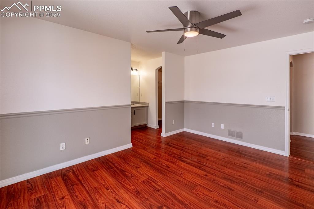 Spare room with arched walkways, dark wood-style flooring, and ceiling fan