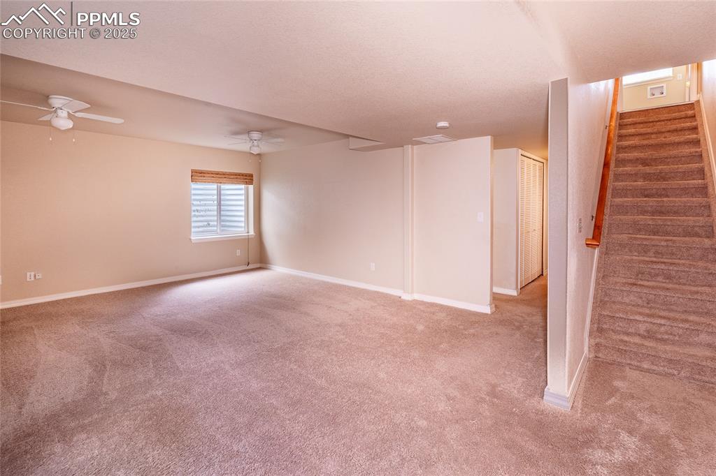 Basement featuring stairs and light carpet
