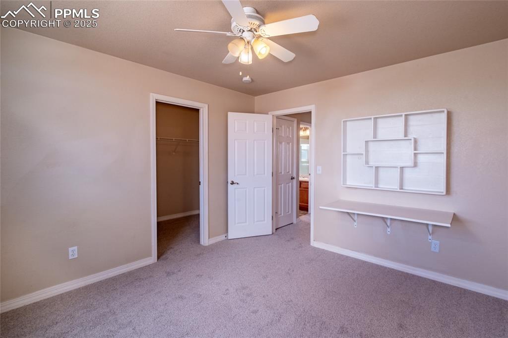 Unfurnished bedroom featuring light carpet, a walk in closet, and ceiling fan