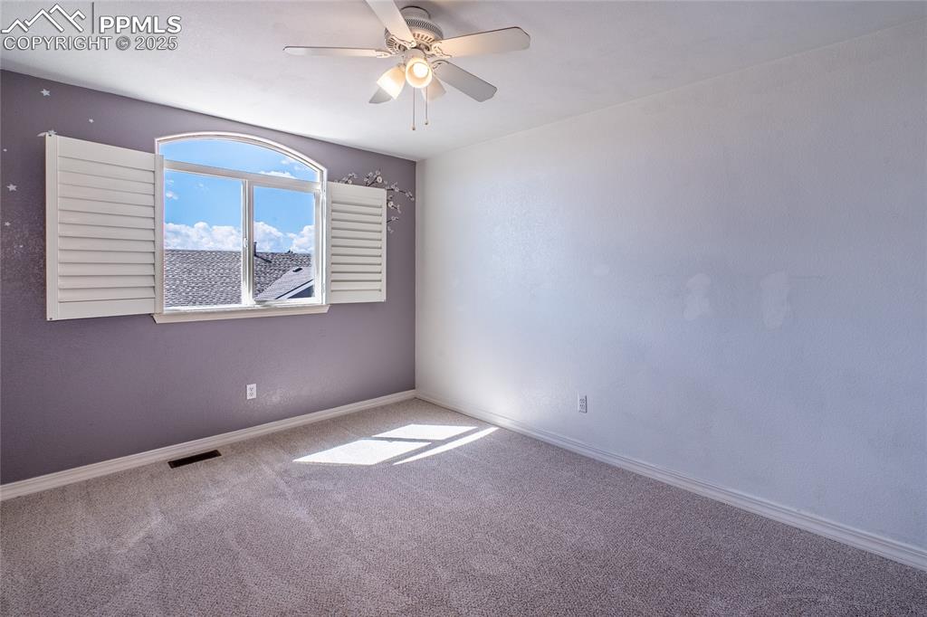 Carpeted empty room featuring baseboards and ceiling fan
