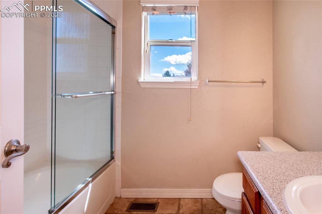 Bathroom with vanity, enclosed tub / shower combo, and light tile patterned floors