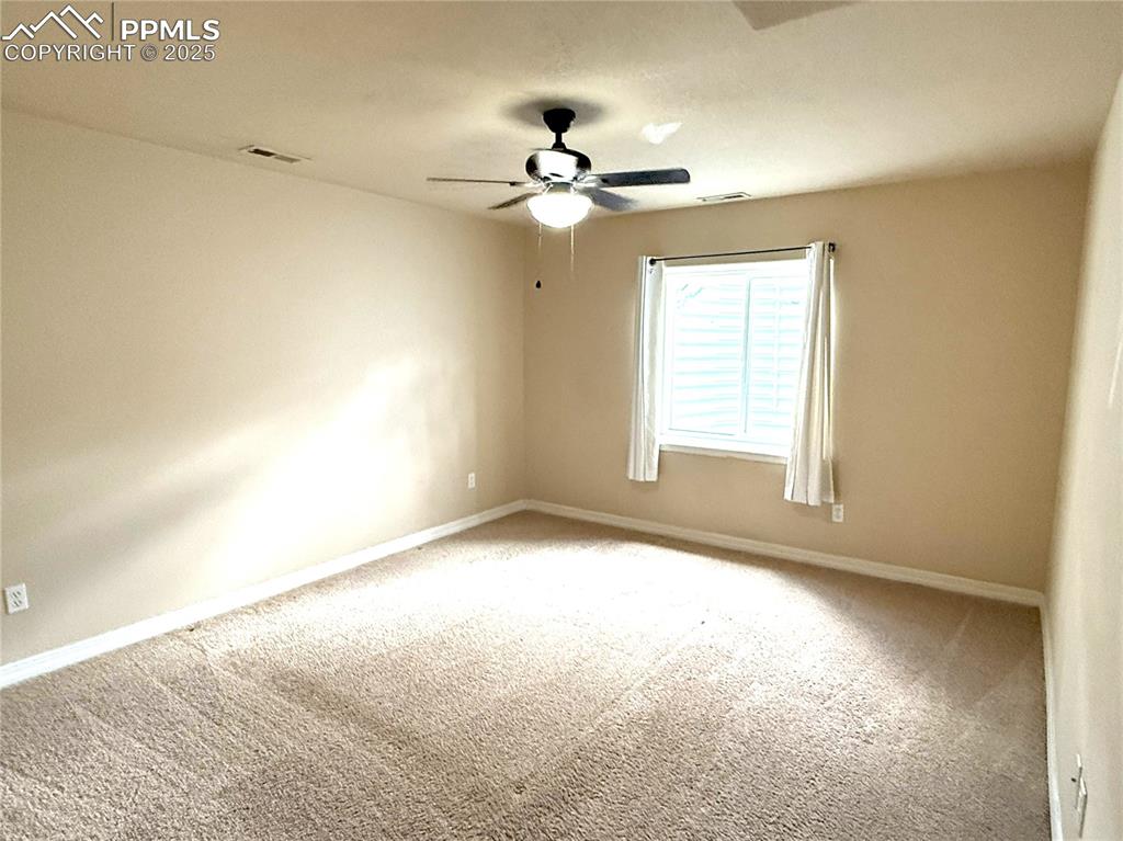 Carpeted spare room featuring baseboards and ceiling fan