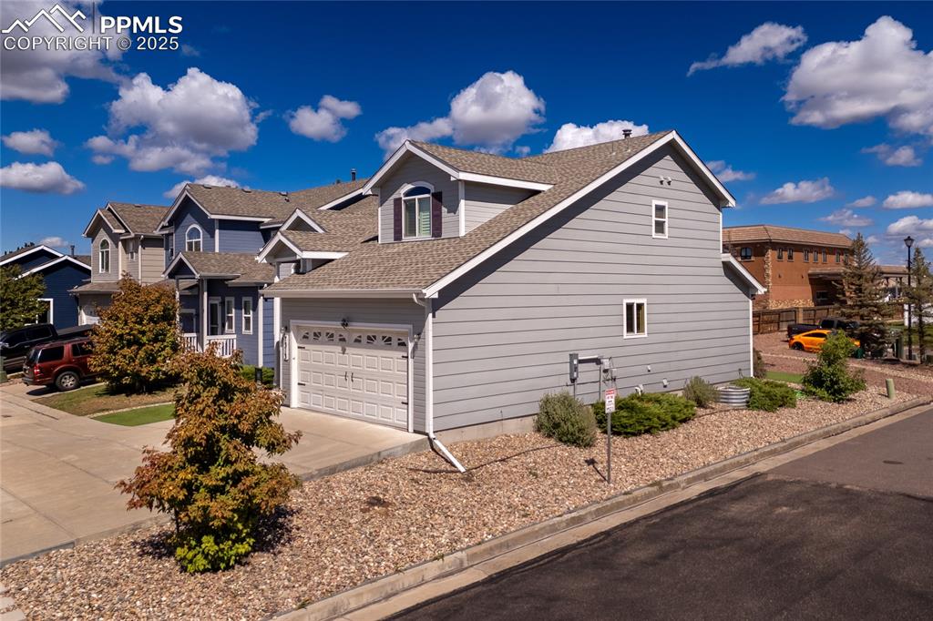 View of home's exterior featuring roof with shingles and driveway