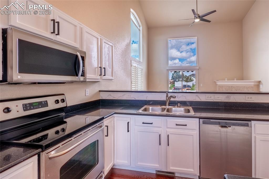 Kitchen with stainless steel appliances, white cabinets, healthy amount of natural light, and a ceiling fan