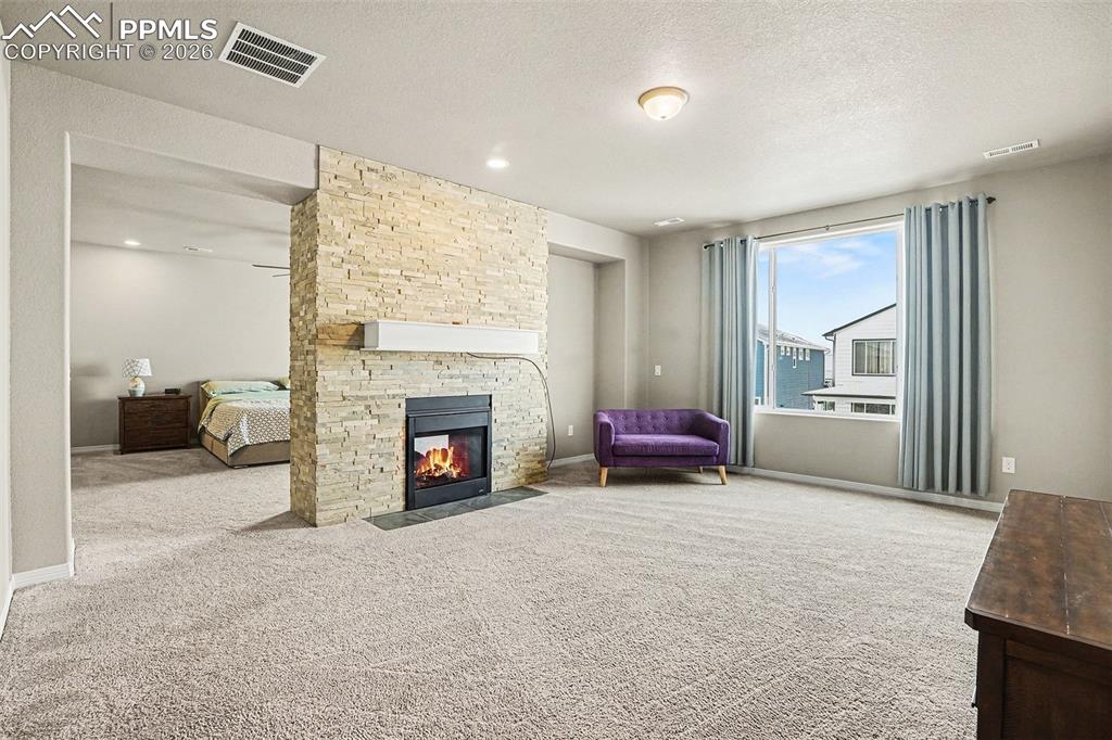 Living room with a textured ceiling, a fireplace, and light carpet