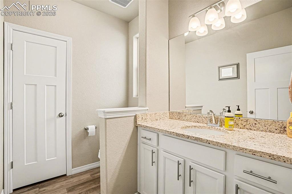 Half bath with vanity, dark wood-style floors, and a textured wall