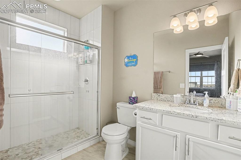 Ensuite bathroom featuring plenty of natural light, a shower stall, vanity, and ceiling fan