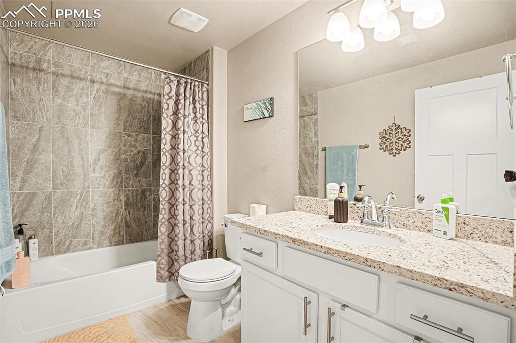 Full bath featuring shower / bath combo, vanity, and a textured wall