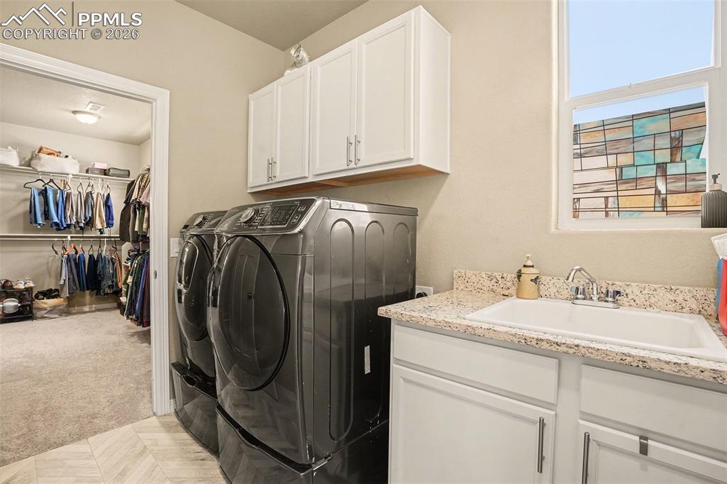 Washroom featuring light colored carpet, cabinet space, and washer and clothes dryer