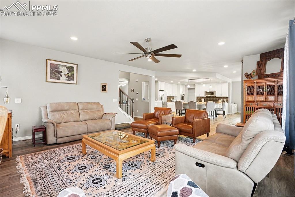 Living area with dark wood-style flooring, recessed lighting, a ceiling fan, and stairs