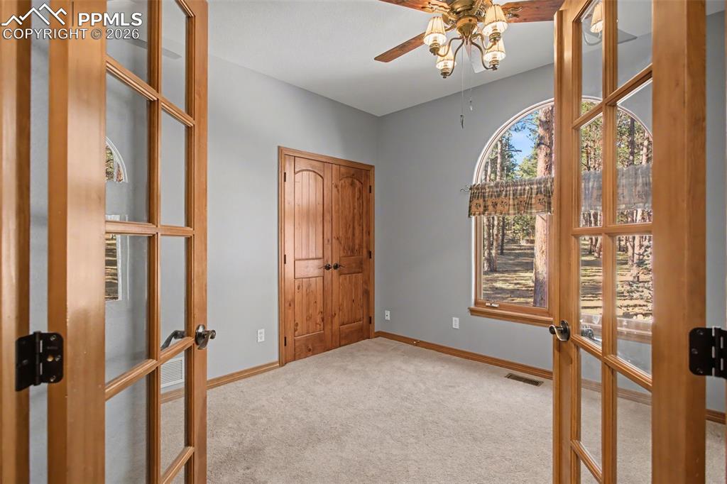 Unfurnished office with french doors, light colored carpet, and ceiling fan
