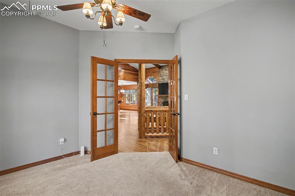 Empty room featuring french doors, ceiling fan, and light carpet