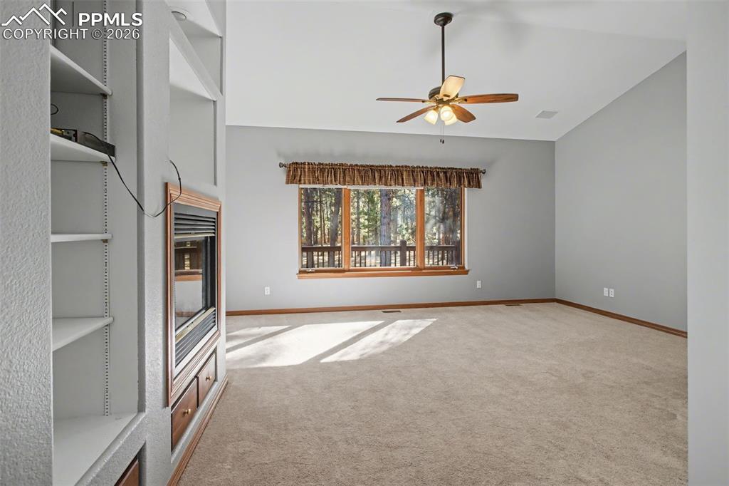 Unfurnished living room with ceiling fan, carpet flooring, and lofted ceiling