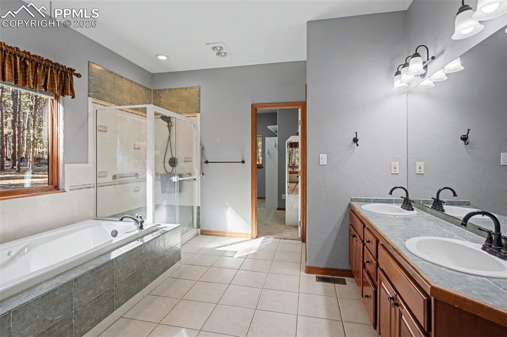 Bathroom with a stall shower, double vanity, light tile patterned floors, and a garden tub