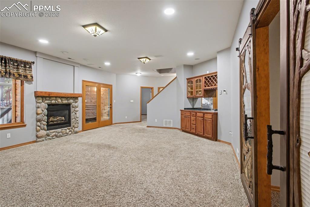 Unfurnished living room with light colored carpet, a fireplace, a barn door, bar, and recessed lighting