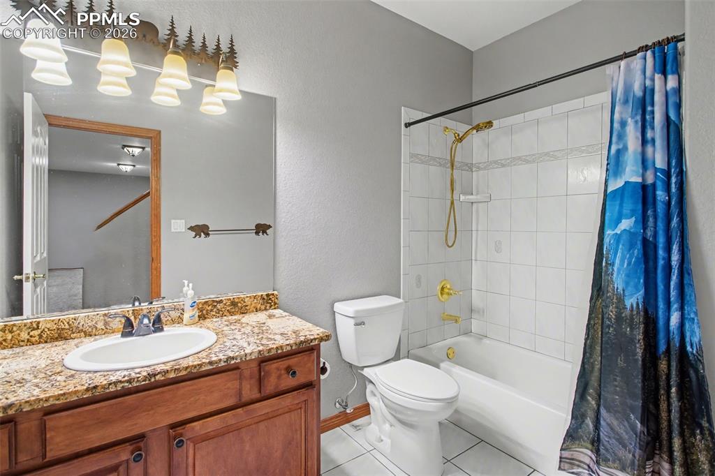Full bathroom featuring vanity, a textured wall, shower / bath combination with curtain, and light tile patterned flooring