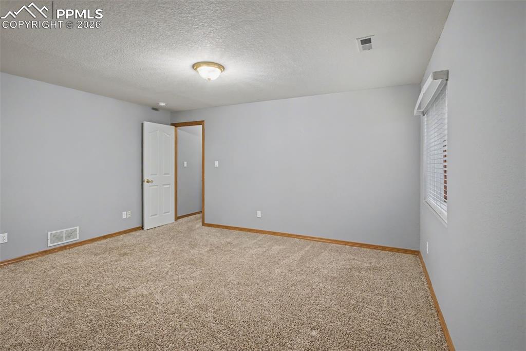 Empty room featuring light carpet and a textured ceiling