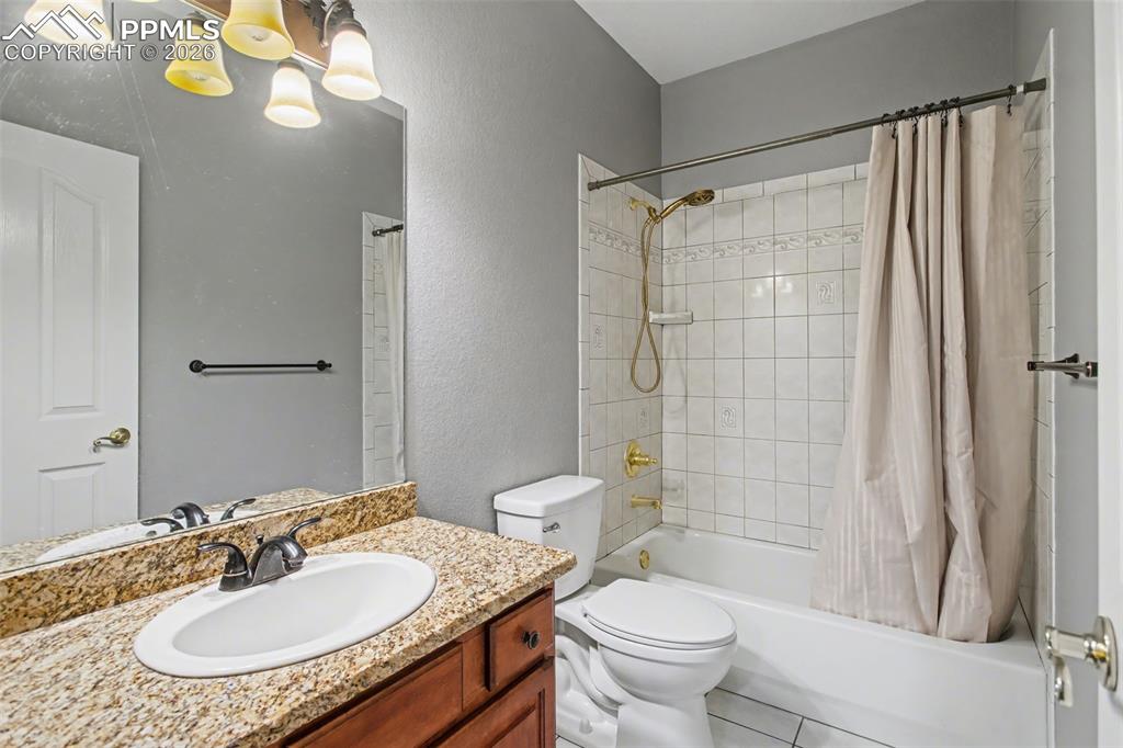 Bathroom featuring vanity, shower / tub combo, a textured wall, and light tile patterned flooring